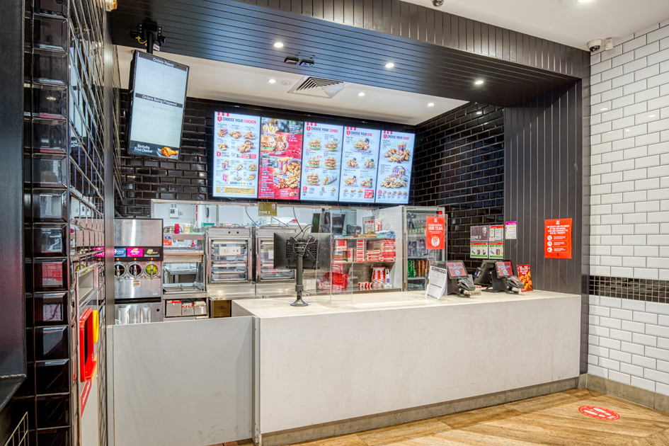 An empty KFC service line with restaurant equipment visible behind the counter